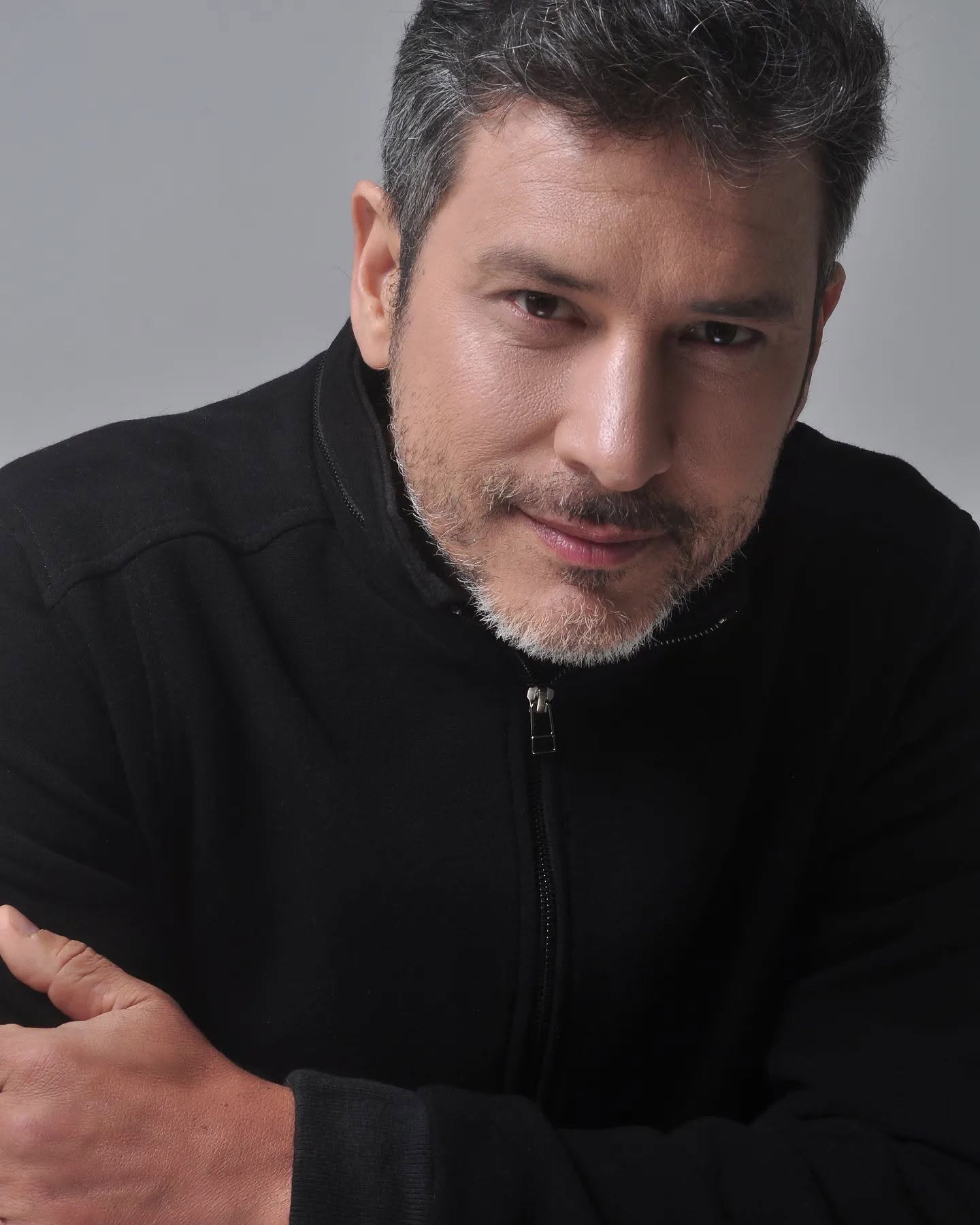 Retrato de Paulo Oliani em preto, diante de um fundo claro.