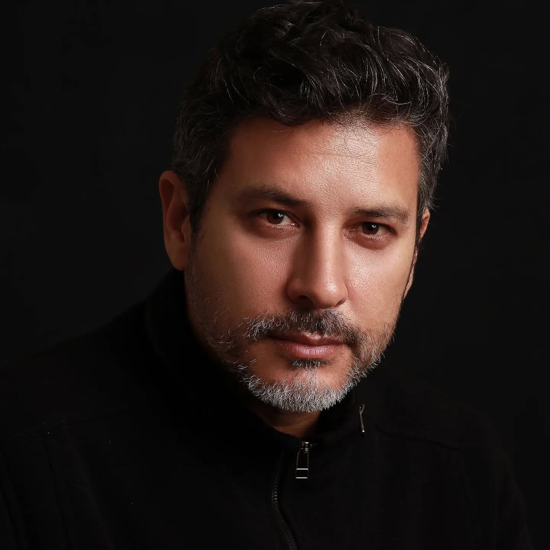 Retrato frontal de Paulo Oliani em fundo escuro.